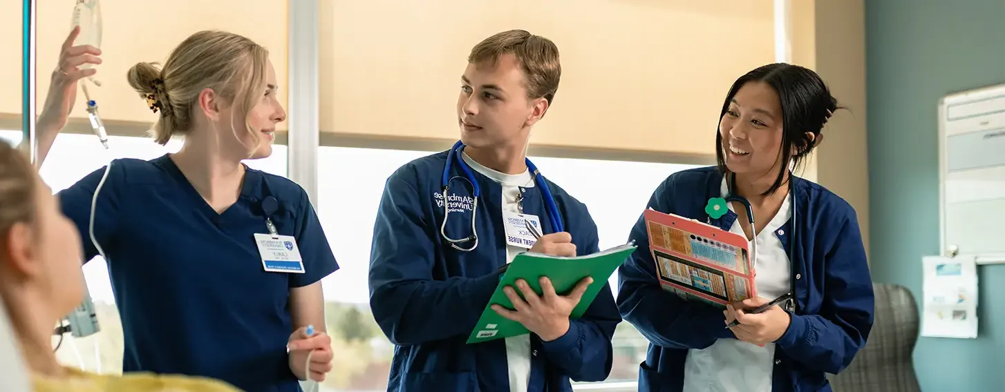 A group of nursing students providing care to a patient in a hospital room.